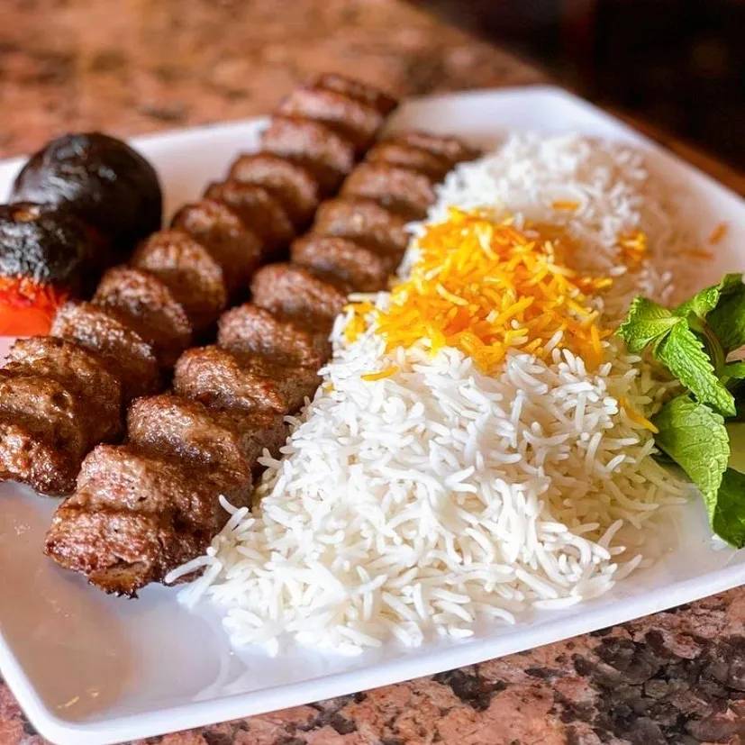 Two kebabs with rice on a square plate